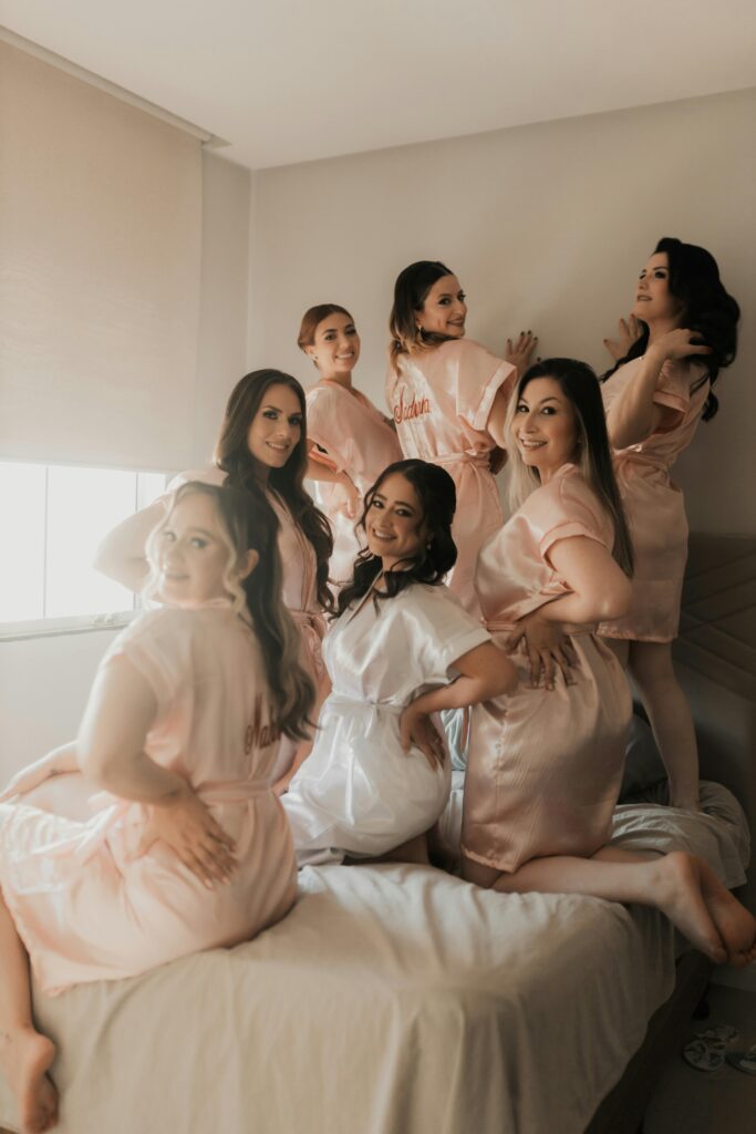 Group of bridesmaids in matching robes enjoying pre-wedding preparations indoors.